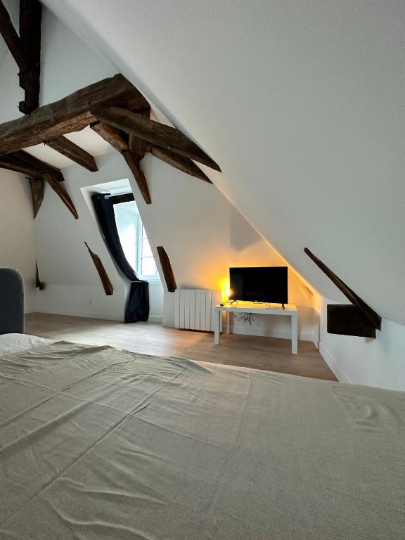 Schlafzimmer mit einem Bett und einem Schreibtisch mit einem TV in der Unterkunft T2 atypique et chaleureux in Baugé