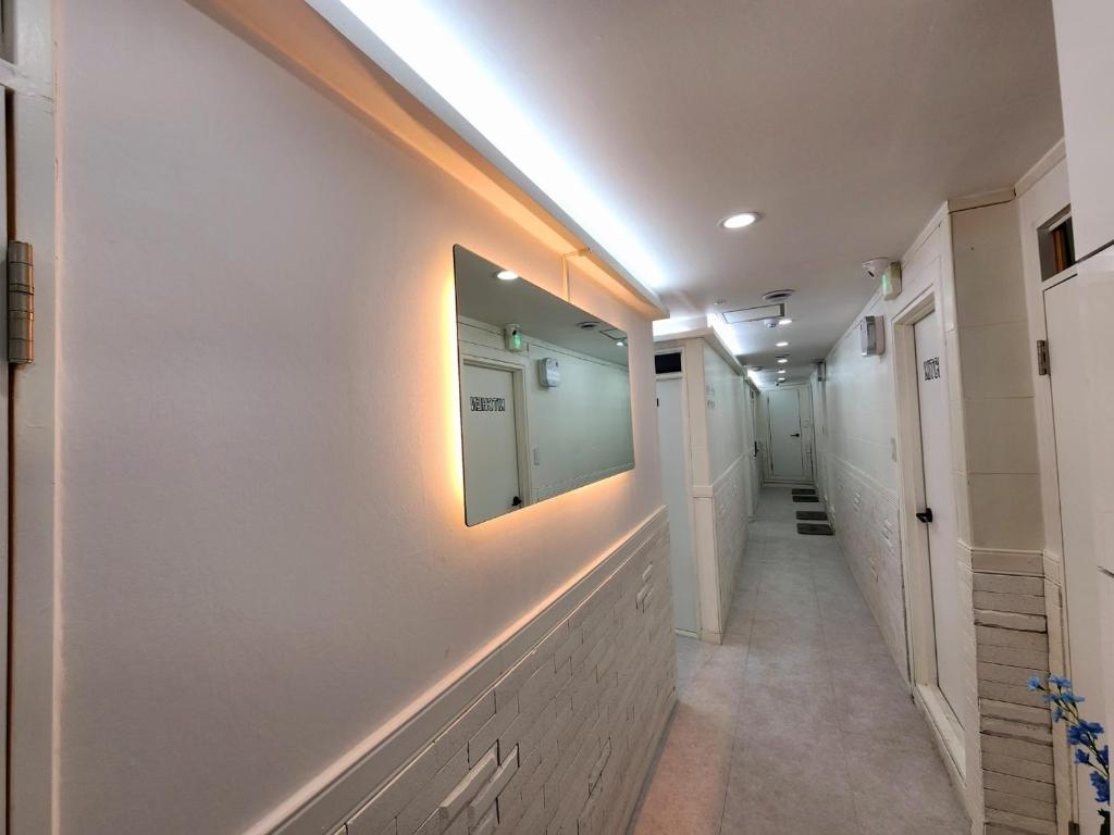 a hallway with white walls and a mirror on the wall at Friends Yul For men in Seoul