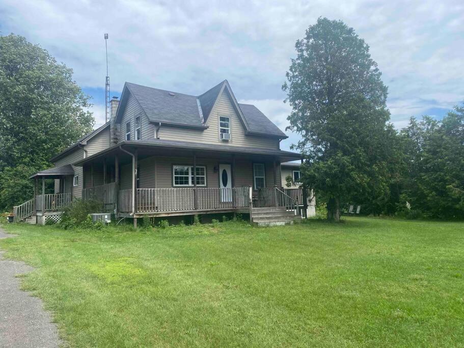 a house with a porch and a grass yard at 4 bedroom apartment on 75 acre farm in Tillsonburg