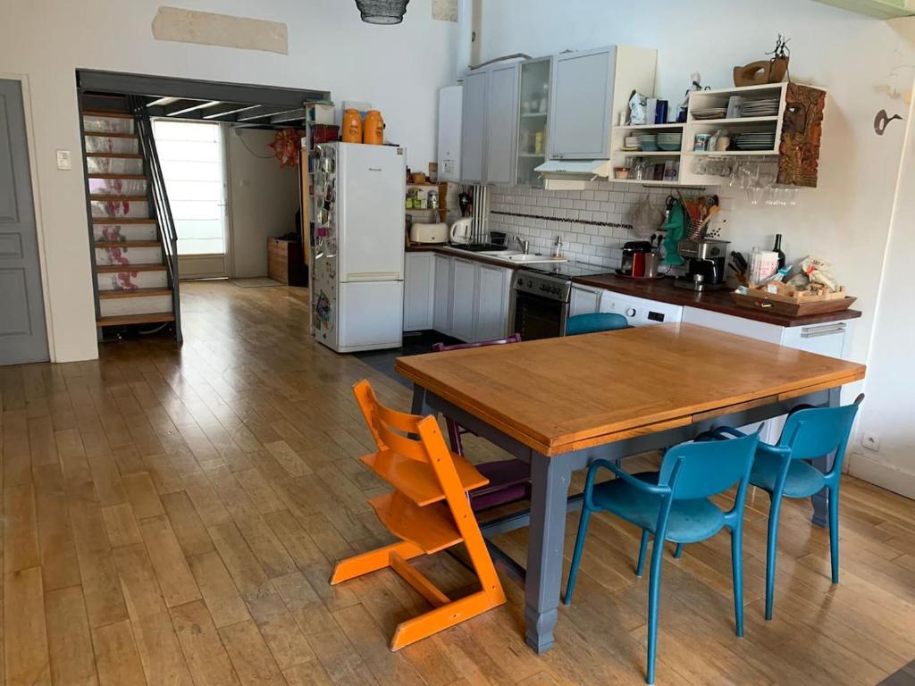 a kitchen with a wooden table and blue chairs at Charmante maison de surfeur in Talence
