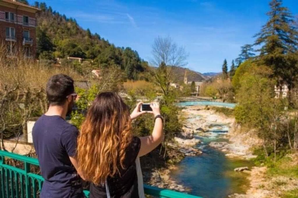 a man and woman taking a picture of a river at Un moment de Détente au cœur de Vals-les-Bains in Vals-les-Bains