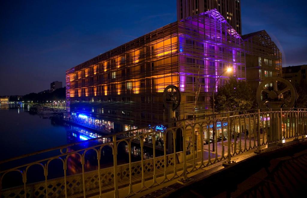 un edificio con luci viola sopra, vicino a un fiume di Holiday Inn Express Paris-Canal De La Villette, an IHG Hotel a Parigi