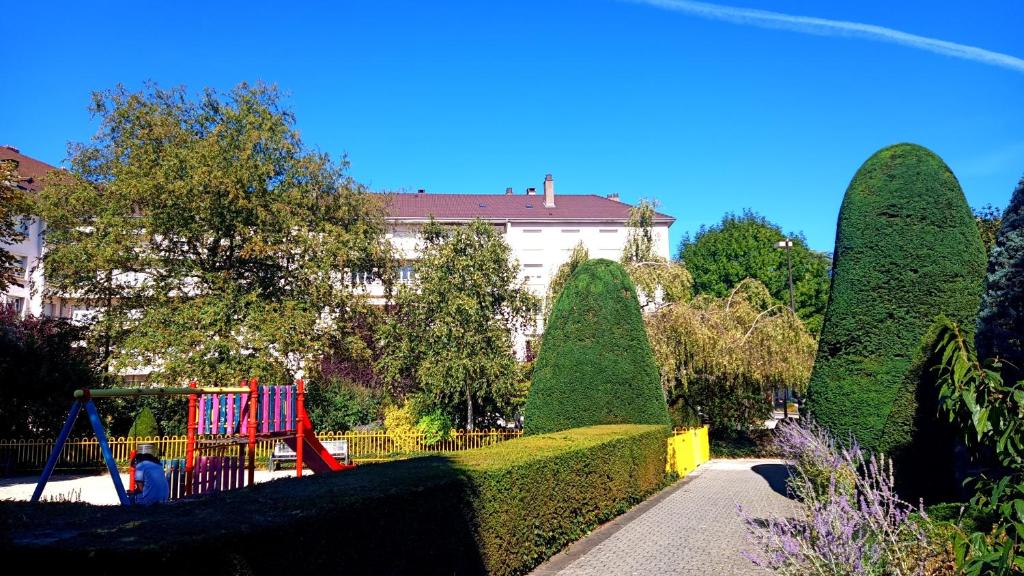 een park met een speeltuin en hagen en een gebouw bij Résidence Le Château in Montbéliard