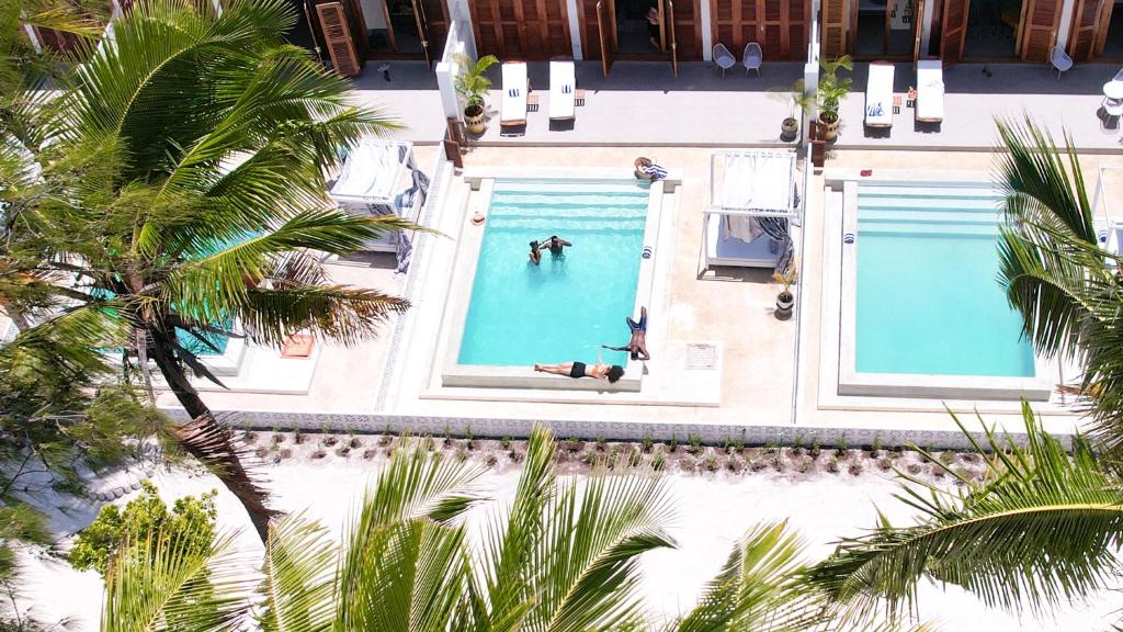 an overhead view of two swimming pools with people in the water at Pili Pili Orient Beach Hotel in Bwejuu