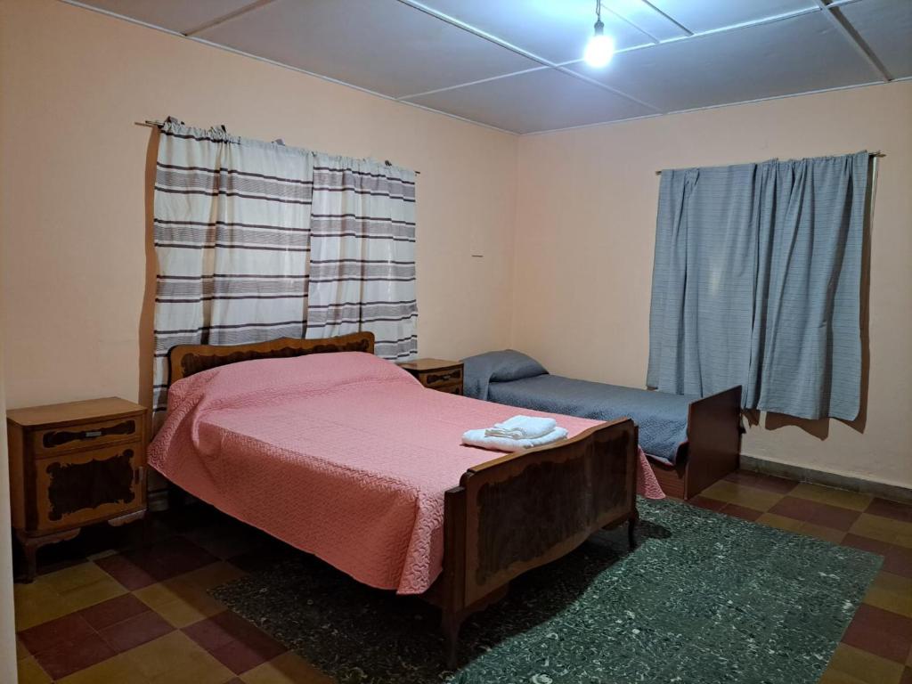 1 dormitorio con 1 cama, 1 silla y 1 ventana en La Casona de la tía en La Consulta