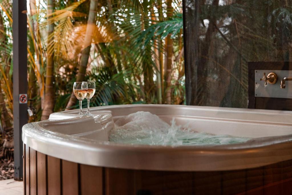 a glass of champagne and a glass of wine in a tub at Lake Russell Lakeside Retreat in Emerald Beach