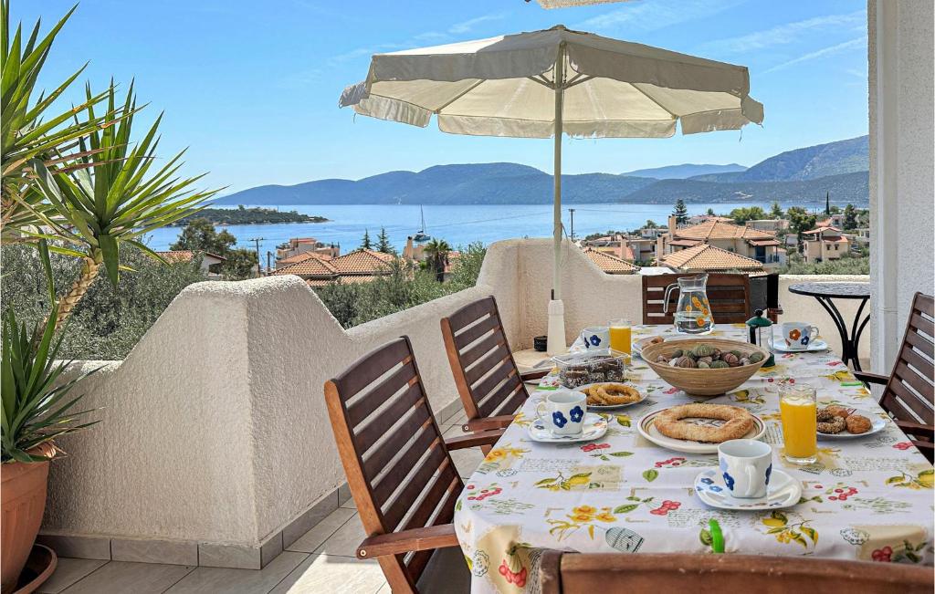 una mesa con comida en un balcón con sombrilla en Nice Apartment In Korfos, Korinthos With Wifi, en Korfos