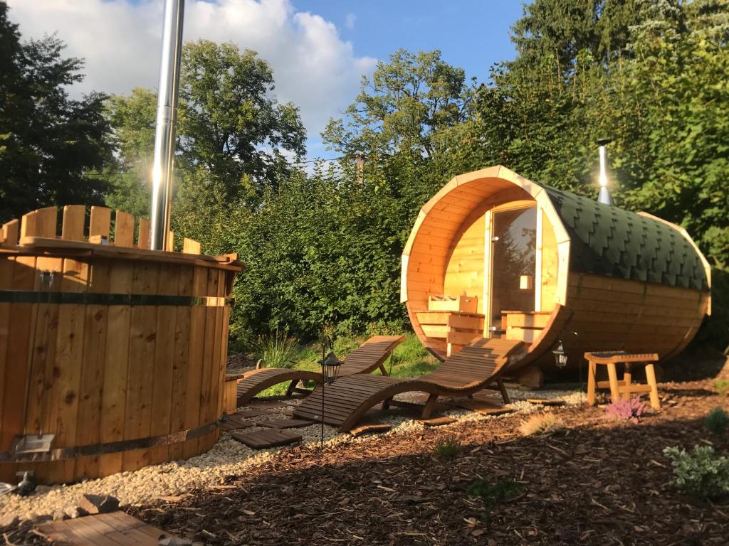 a wooden cabin with chairs and a wooden barrel at Glamping U Lesní víly in Záchlumí