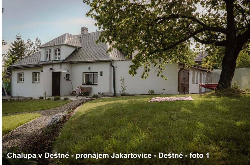 una casa blanca con un árbol en el patio en Chalupa v Deštném 
