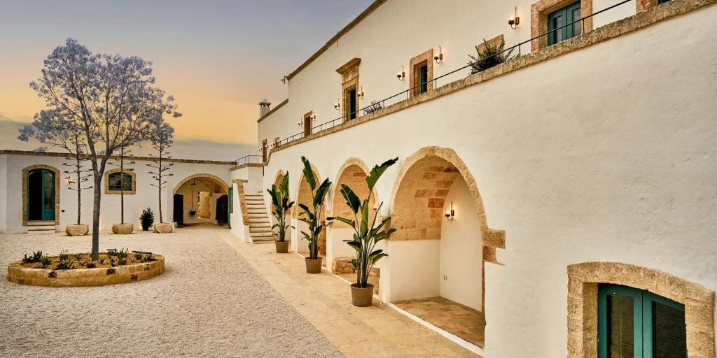 a building with a courtyard with potted plants and a tree at Bambarone La Masseria in Fasano
