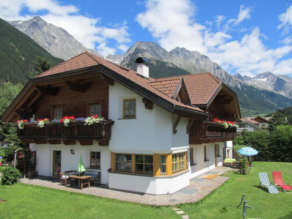 una casa en las montañas con un patio verde en Hellweger Apartments, en Anterselva di Mezzo