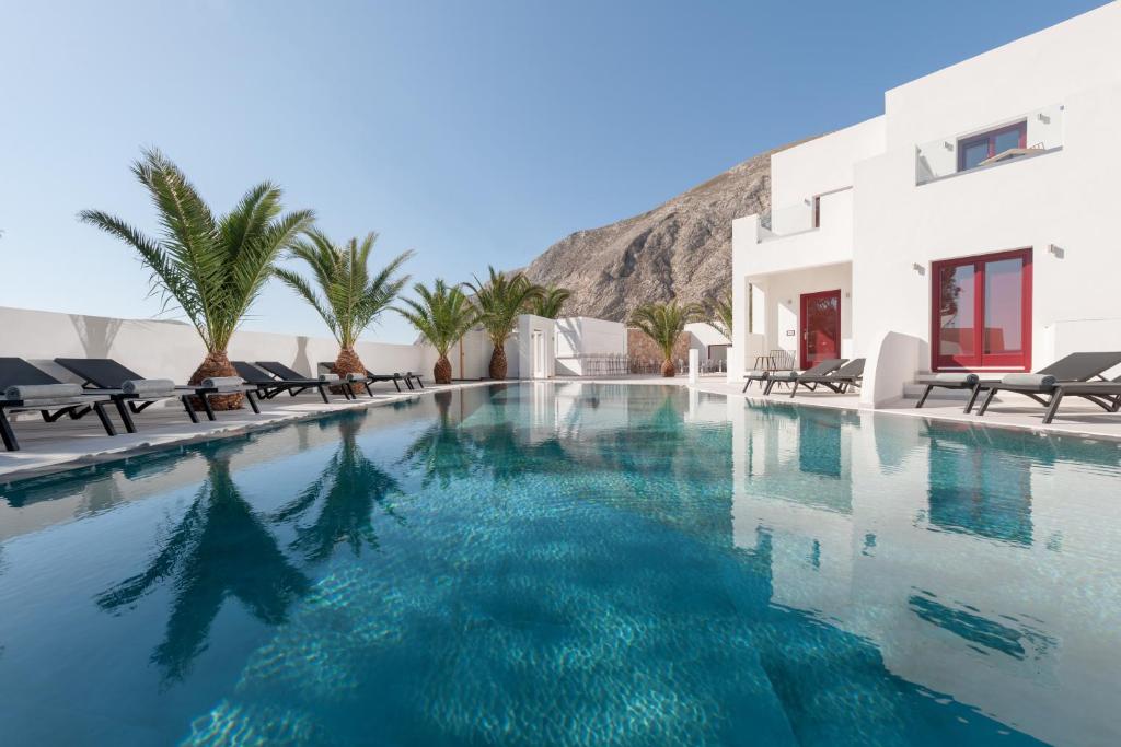 una piscina con acqua blu di fronte a un edificio di MAR n MAR CROWN HOTEL-SUITES a Kamari