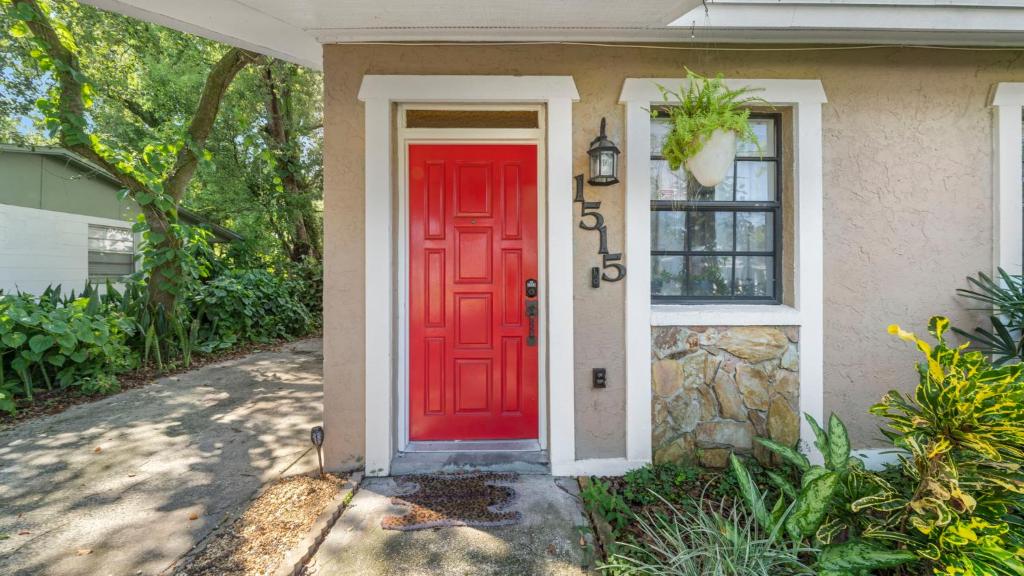 una puerta roja en una casa con en Zen Jungle House by Busch Gardens Sleeps 10 with Outdoor Games and bikes!, en Tampa