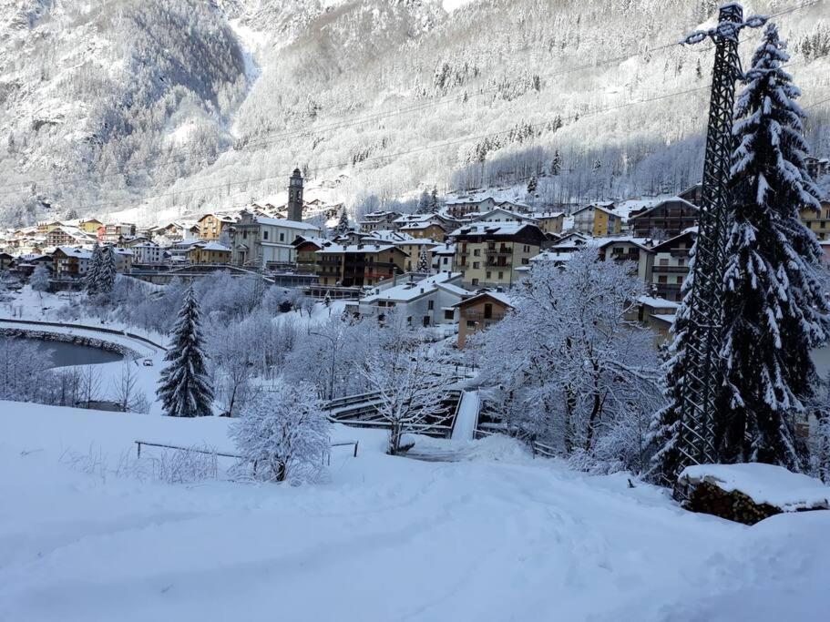a town covered in snow with a bridge and mountains at Mansarda Carona in Carona