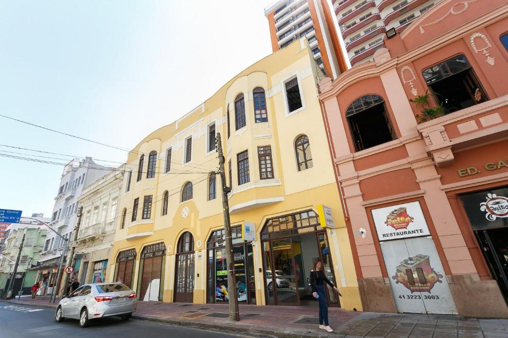 a woman standing on a street corner in front of buildings at All You Need in Curitiba