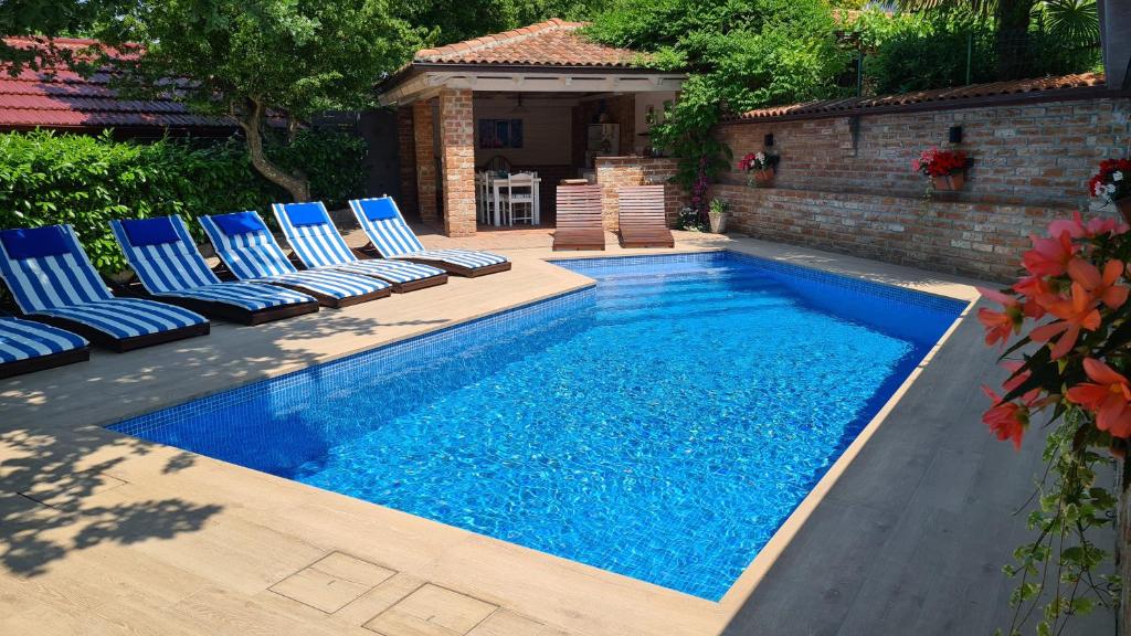 a swimming pool with lounge chairs next to a house at Villa Amalia Apartments in Malinska