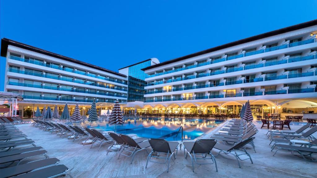 a hotel with chairs and a swimming pool at night at Letoile Beach Hotel in Marmaris