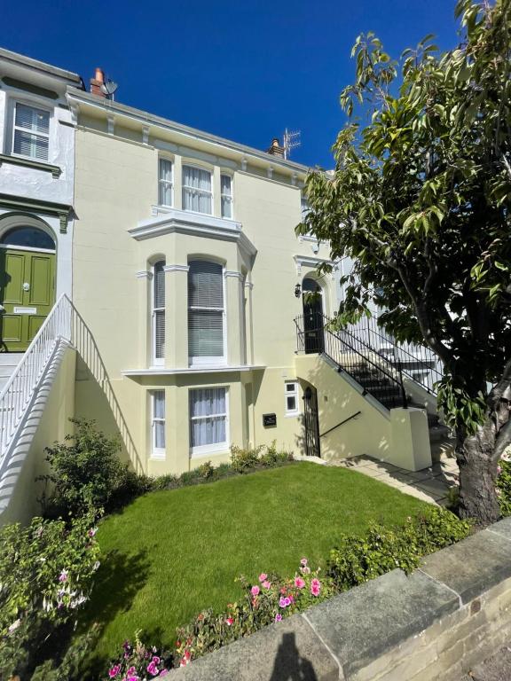 een groot wit huis met een groene tuin bij Garden flat in 'Little Chelsea' in Eastbourne