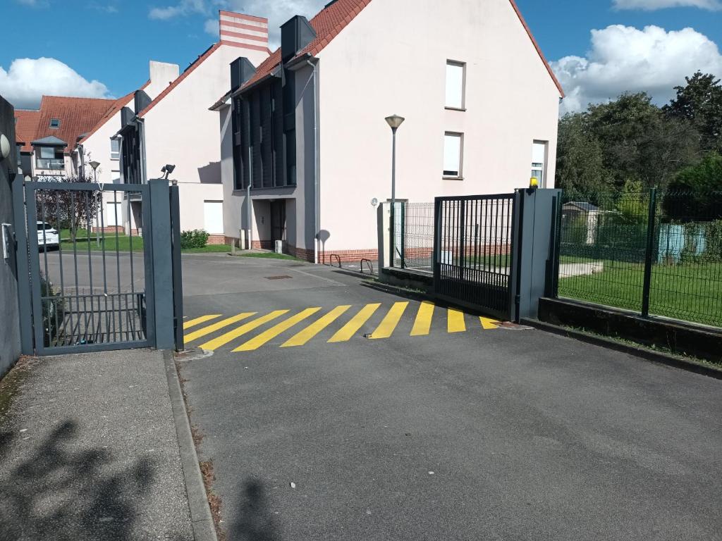 a gate in front of a white building with a flag at résidence la clairière aux portes de la baie de Somme in Abbeville