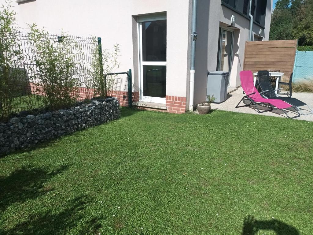 a yard with a pink chair and a table at résidence la clairière aux portes de la baie de Somme in Abbeville