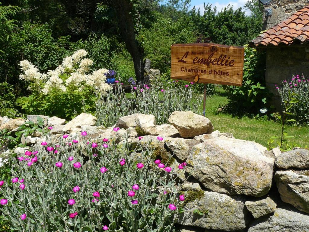 a sign in a garden with pink flowers and rocks at L'embellie in Bertignat