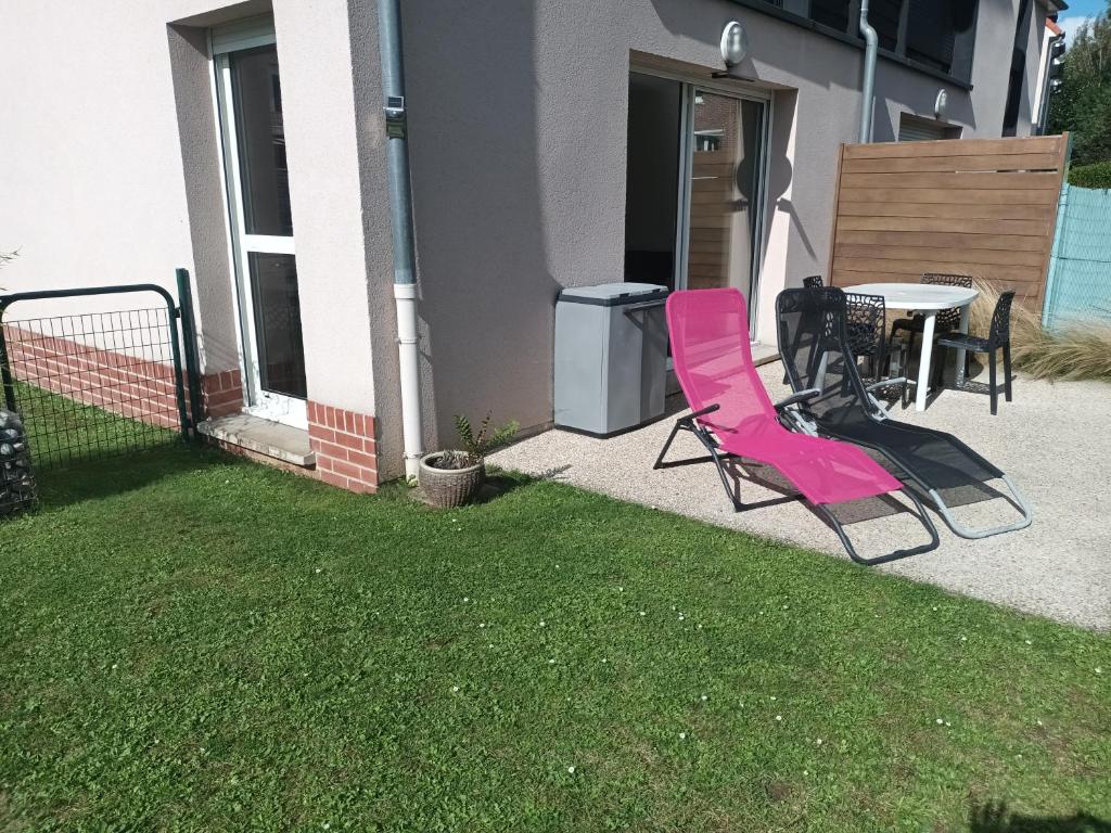 a patio with pink chairs and a table in a yard at résidence la clairière aux portes de la baie de Somme in Abbeville