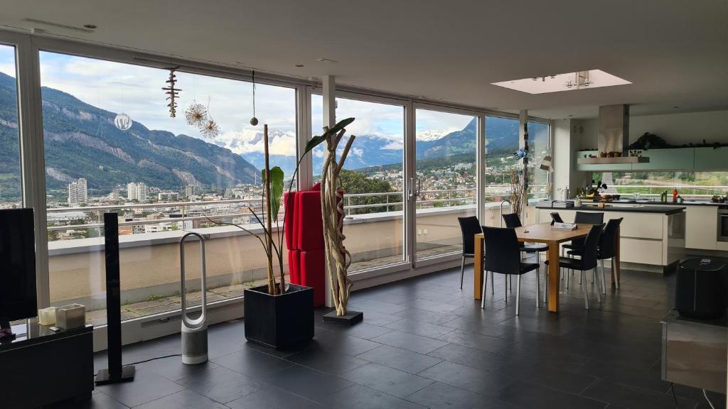 Zimmer mit einem Tisch und Stühlen sowie einem großen Fenster in der Unterkunft Vesmira_1 in Chur