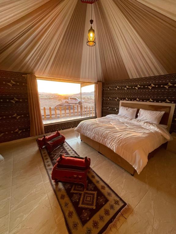 a bedroom with a bed and a large window at Zawaideh desert Camp in Wadi Rum