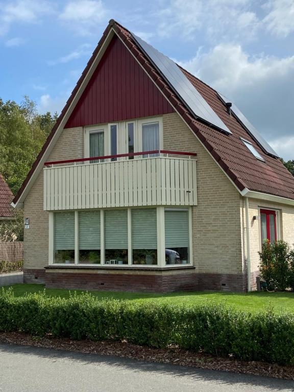 una casa con techo rojo y garaje en Heerlijk genieten. en Hoogersmilde