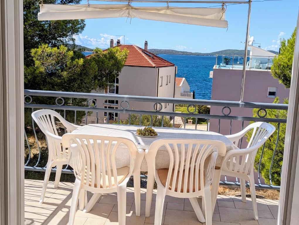 a table and chairs on a balcony with a view of the water at Apartmani Petković in Zaboric