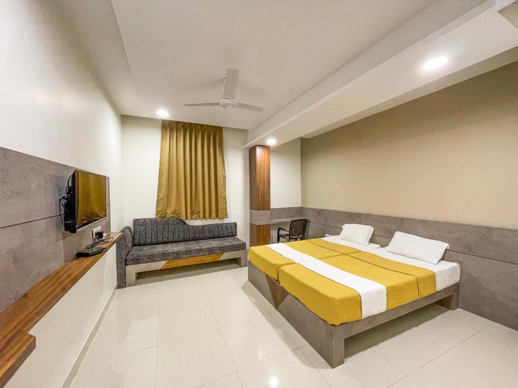a bedroom with a bed and a tv and a couch at Hari Om Residency in Bhuj