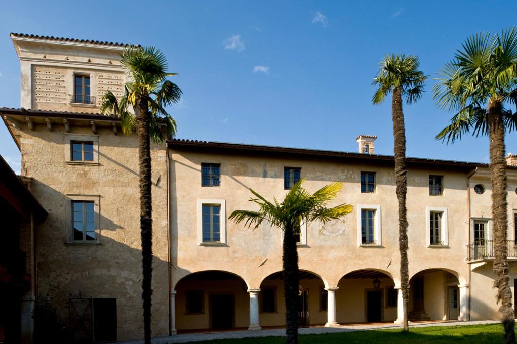 a large building with palm trees in front of it at L'Unicorno Agriturismo in bedizzol
