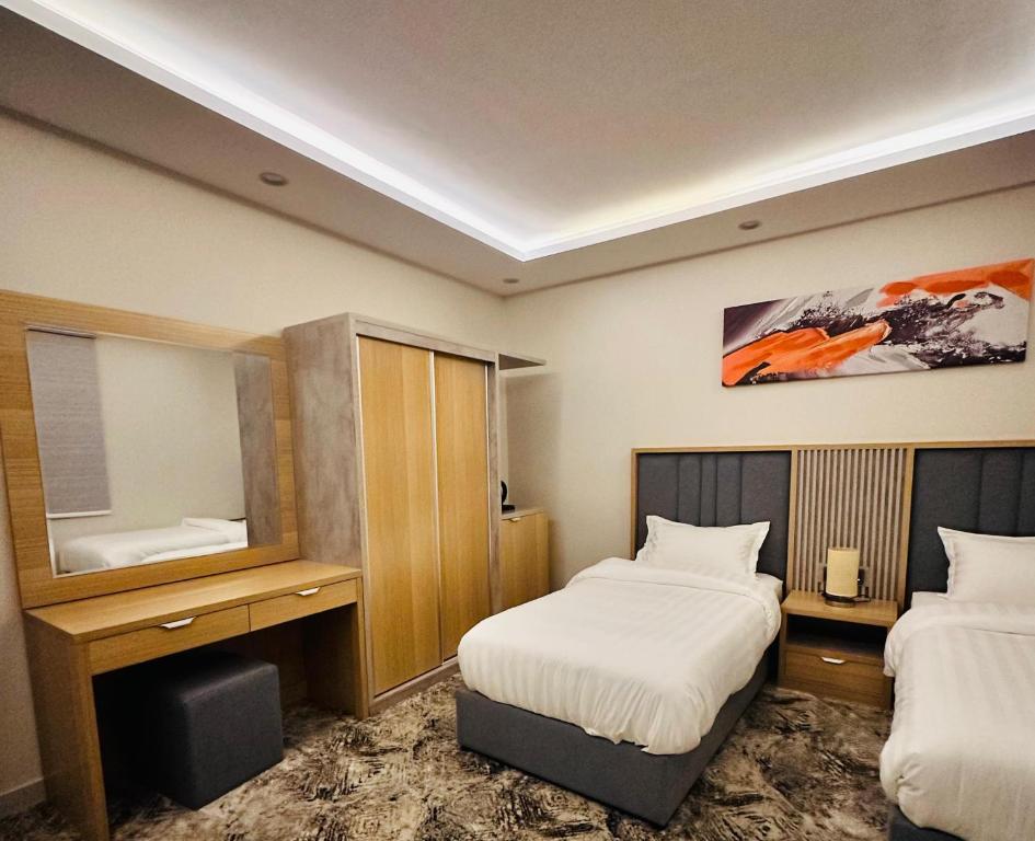 ein Hotelzimmer mit 2 Betten und einem Spiegel in der Unterkunft أجنحة هدوء وصول ذاتي in Medina