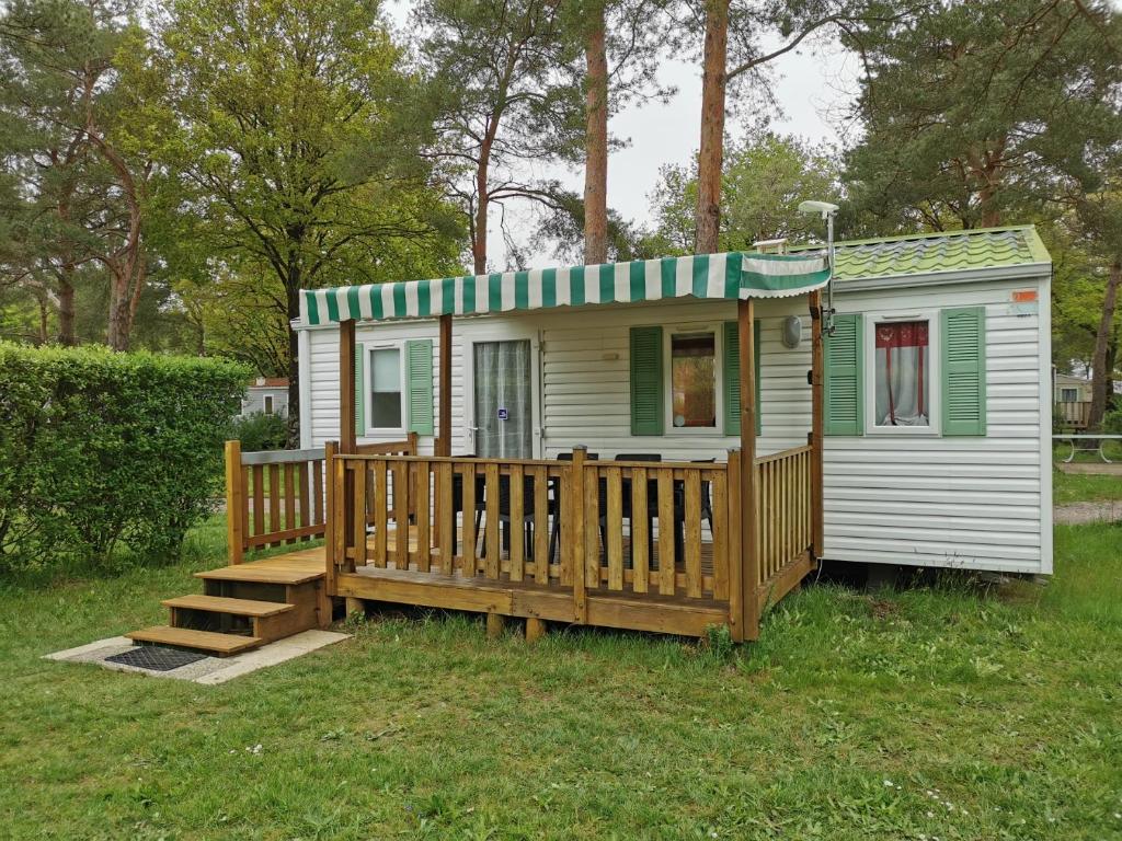 une petite maison avec une terrasse couverte et une terrasse dans l'établissement Mobil Home 4 pers proche Puy du Fou et Montaigu (Vendée 85), à La Boissière-de-Montaigu