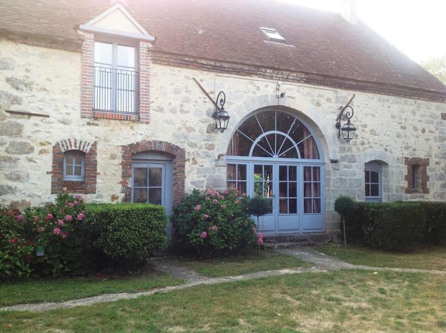 a stone house with a blue door and some bushes at Le Foulon - Moulin de Charme - 1 heure 30 de Paris in Saint-Hilaire-les-Andrésis