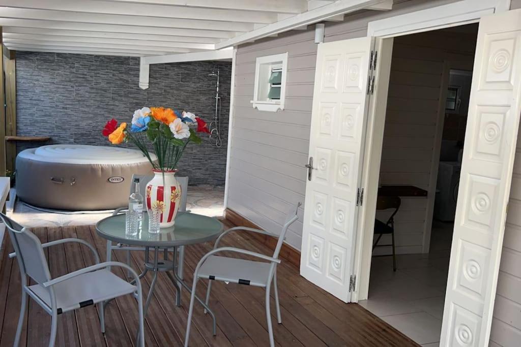 a patio with a table and chairs and a tub at Villa Sissy: T2 avec jaccuzzi in Sainte-Anne