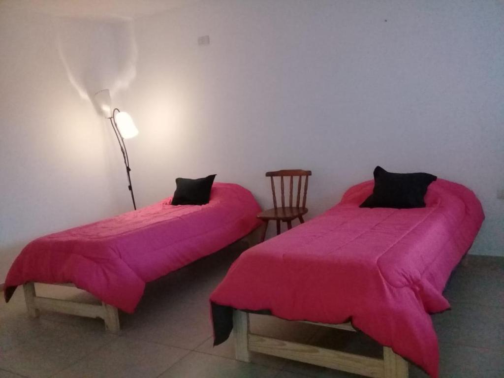 two beds with pink covers in a room at Departamento monoambiente centro pb nuevo sencillo Av Belgrano D3 in Marcos Juárez