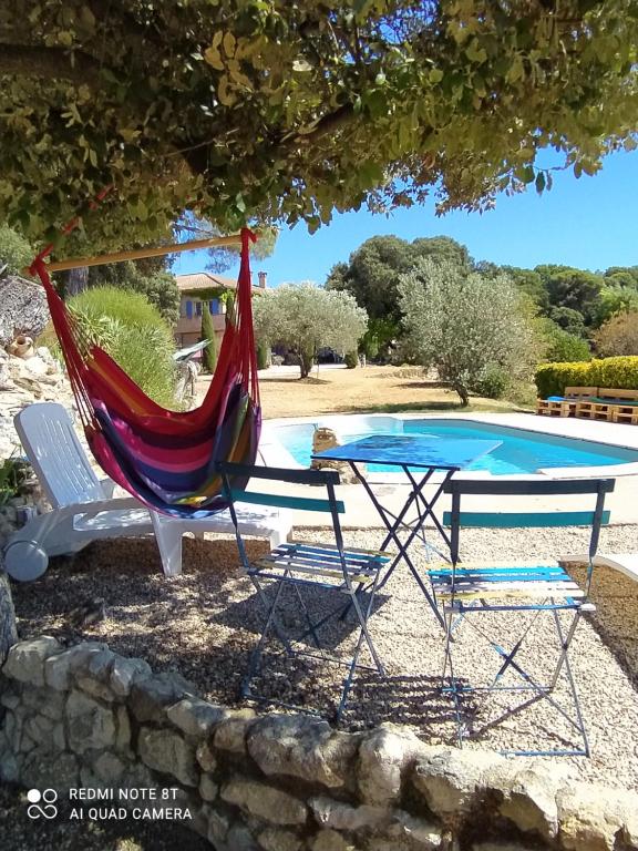 uma rede de descanso e uma mesa e cadeiras ao lado de uma piscina em La maison de Nazig em Pertuis