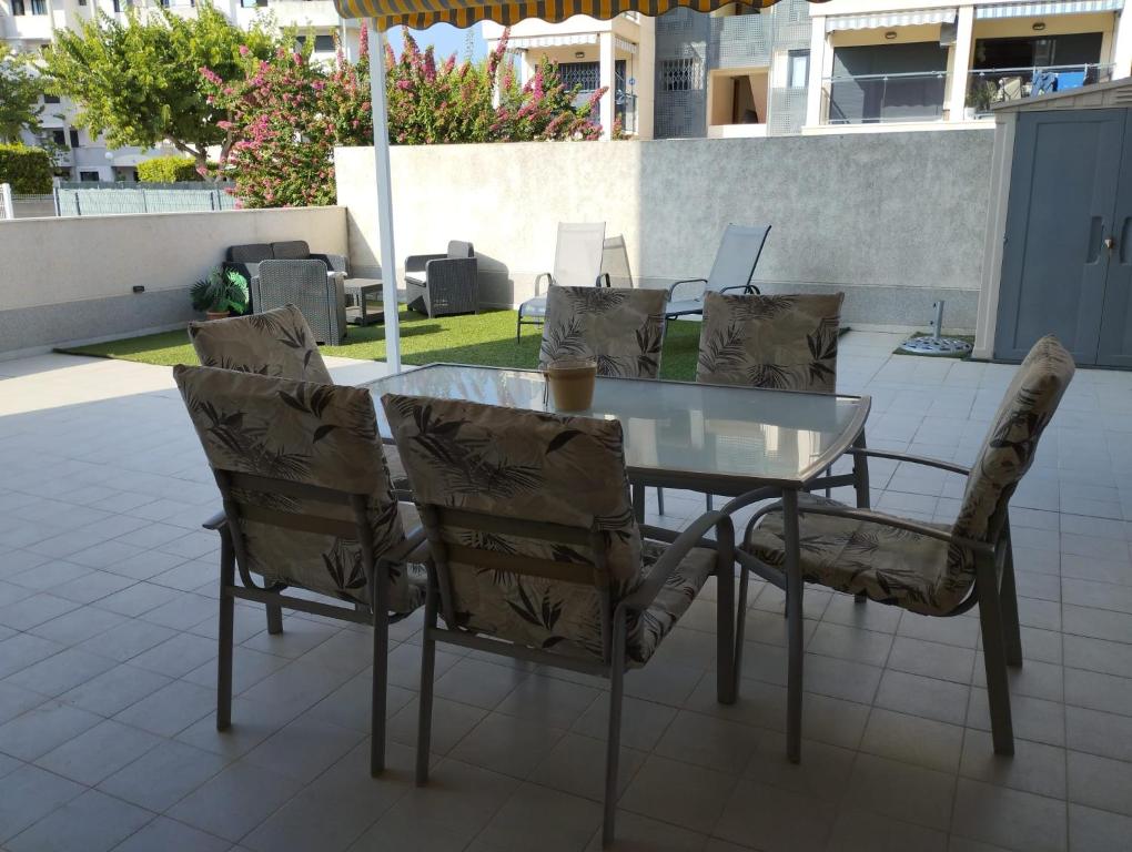une table et des chaises en verre sur la terrasse dans l'établissement APARTAMENTO NEPTUNO - CANET DE BERENGUER, à Canet d'En Berenguer