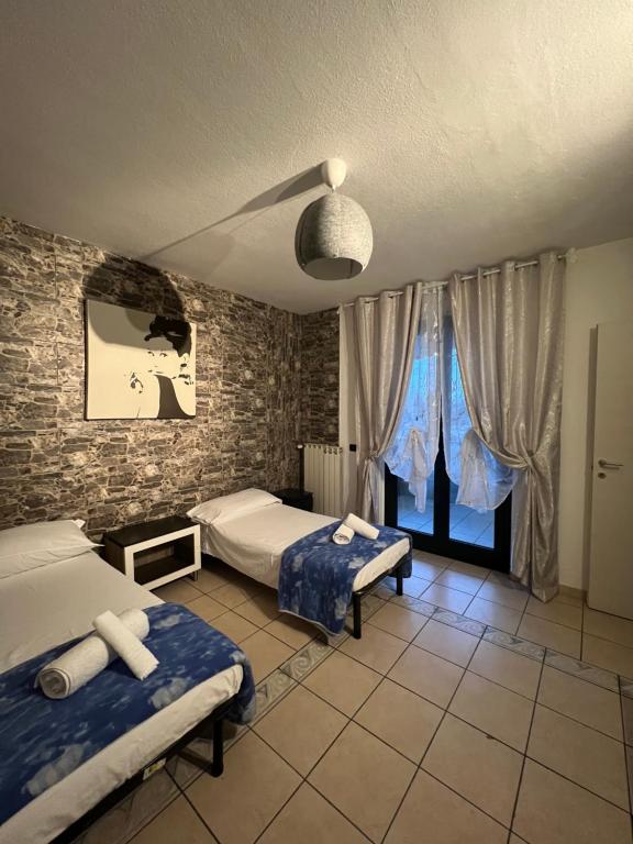 een slaapkamer met 2 bedden en een bakstenen muur bij Affittacamere House in Rho