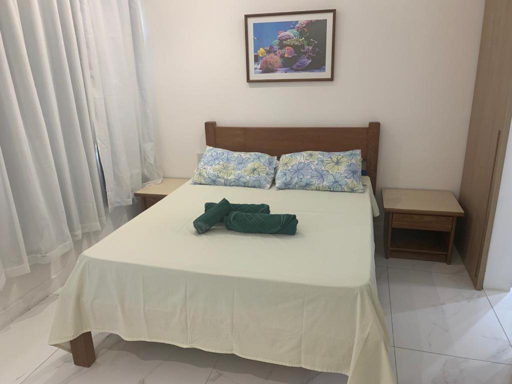 1 dormitorio con 1 cama grande con sábanas y almohadas blancas en Apartamento Princesa Isabel, en Salvador