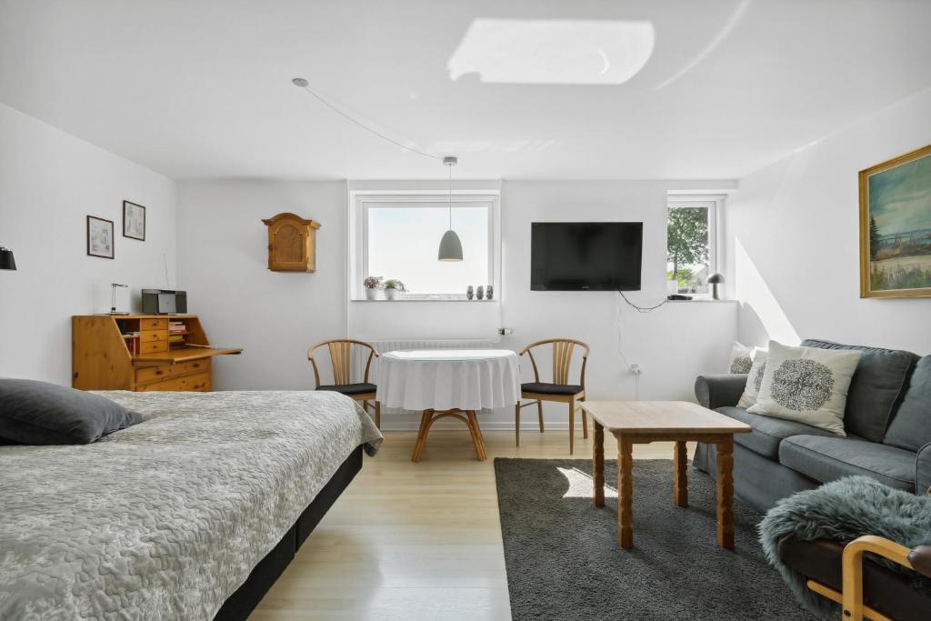 Sala de estar con cama, sofá y mesa en Kastanievejens overnatning, en Svendborg