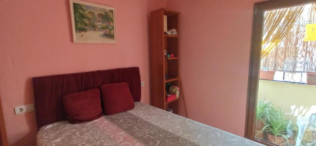 a bedroom with pink walls and a bed with red pillows at Comfort Zone in Órgiva