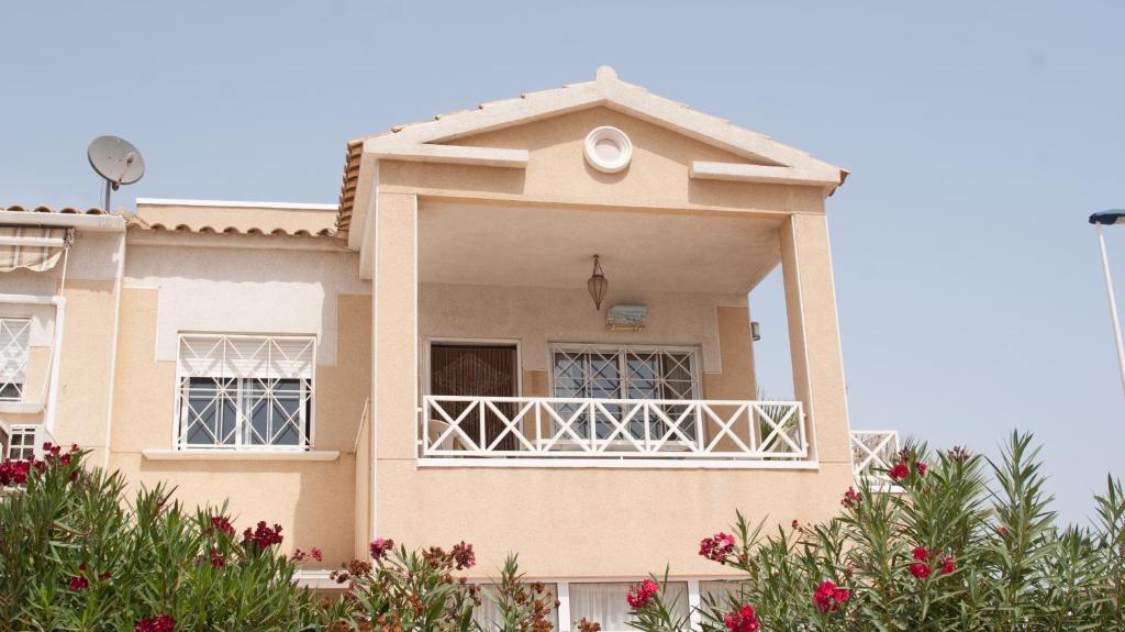 a house with a balcony and flowers in front of it at Casa Vromans Alto in Torrevieja