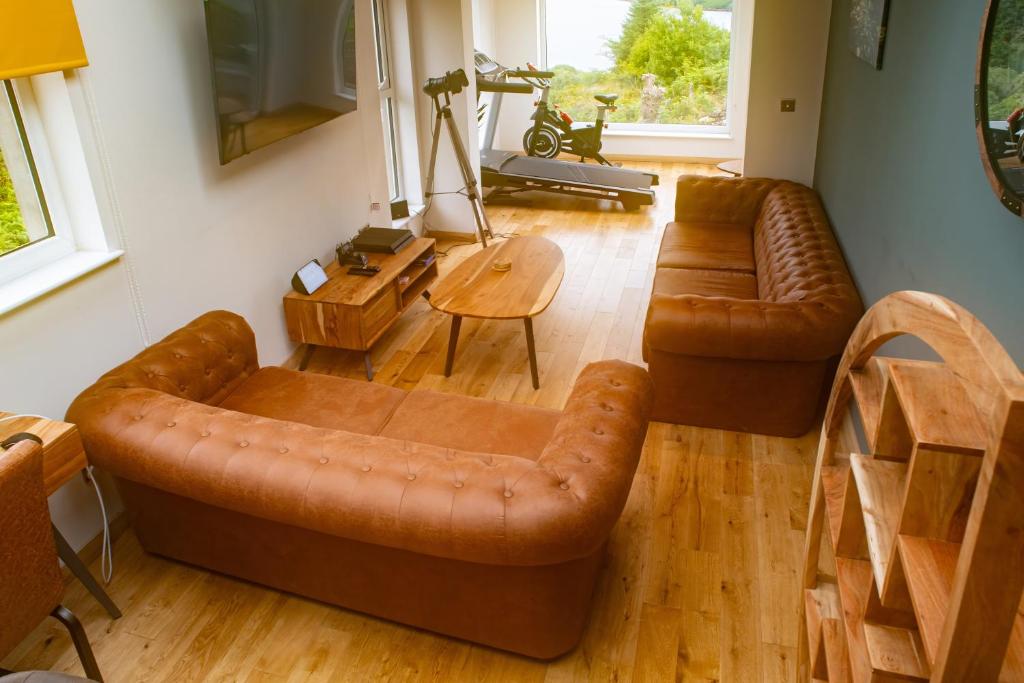 a living room with two leather couches and a table at Luxury Cottage With Stunning Views Near Fairy Pools! in Carbost