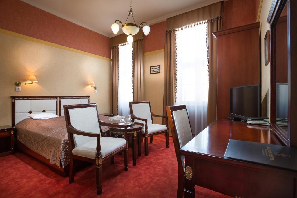 Habitación de hotel con cama, mesa y sillas en Nelson Hotel, en Hajdúszoboszló