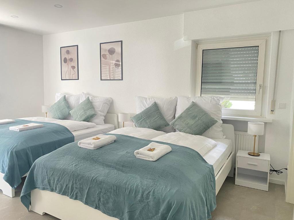 Dos camas en una habitación blanca con toallas. en Lux Apartment near Frankfurt!, en Mörfelden-Walldorf