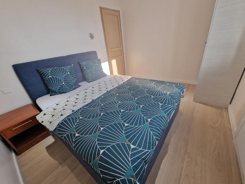 una camera da letto con un letto con un piumone blu e bianco di Appartement 2 chambres près de Genève a Contamine-sur-Arve