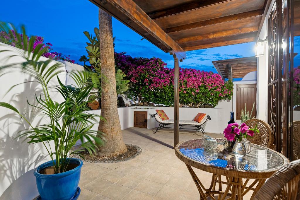een patio met een tafel, stoelen en bloemen bij Villa Munay in Puerto del Carmen