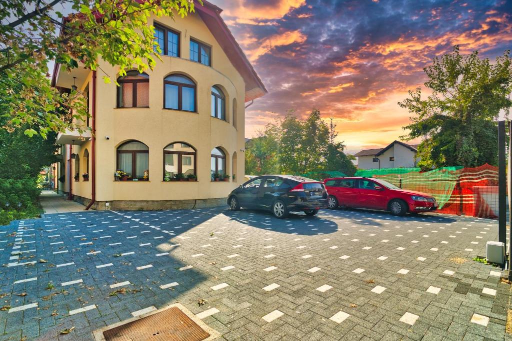 zwei Autos auf einem Parkplatz vor einem Gebäude geparkt in der Unterkunft Apartamente Simona Brasov in Braşov